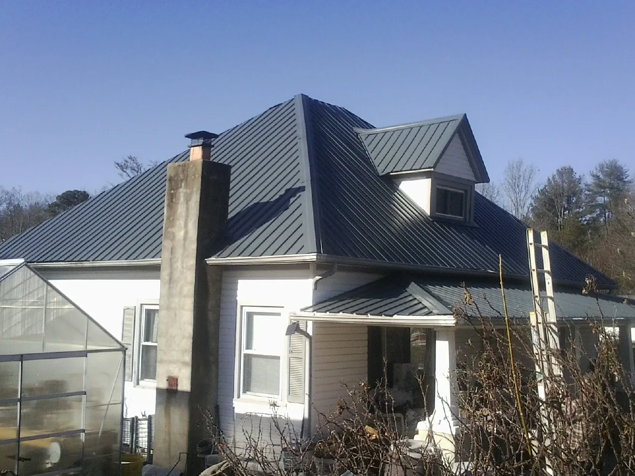 Dark blue standing seam metal roof on a white farmhouse with dormer — Slate & Tile Roof Repair by Roofing Brothers in Manns Choice