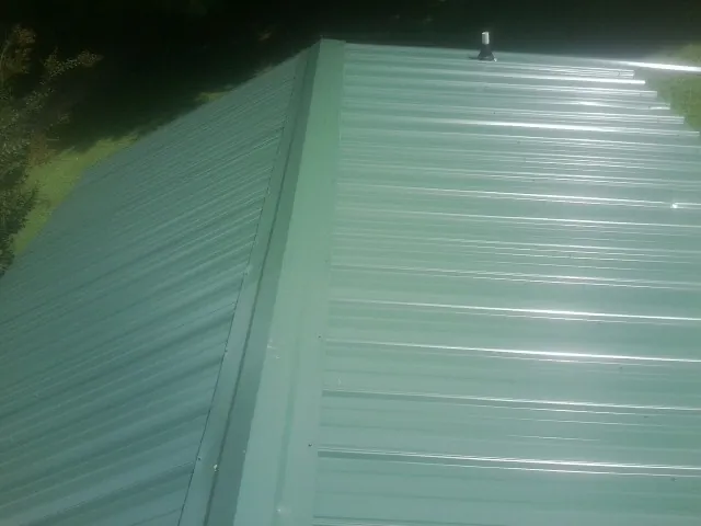 New green metal panels meeting at the ridge of a roof — Flat Roof Repair work by our crew in Manns Choice