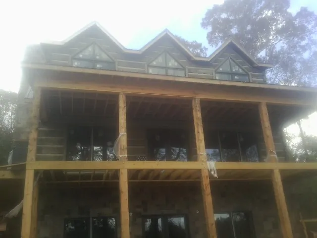 Dormers and porch framing on a large log home under construction — Roof Coating work by our crew in Manns Choice