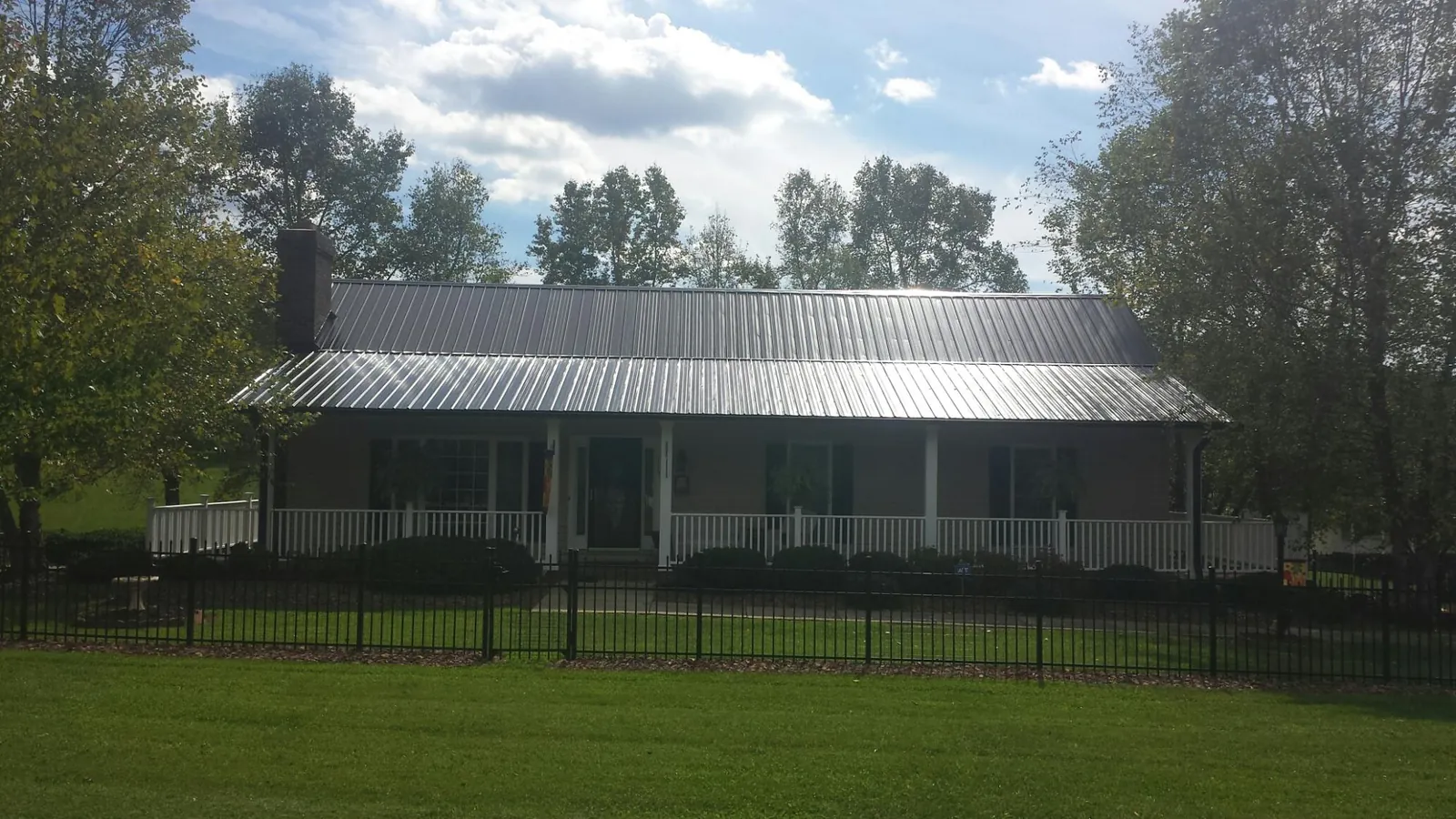Gray metal roof on a brick ranch with a full width front porch — Gutter Guard Installation work by our crew in Manns Choice