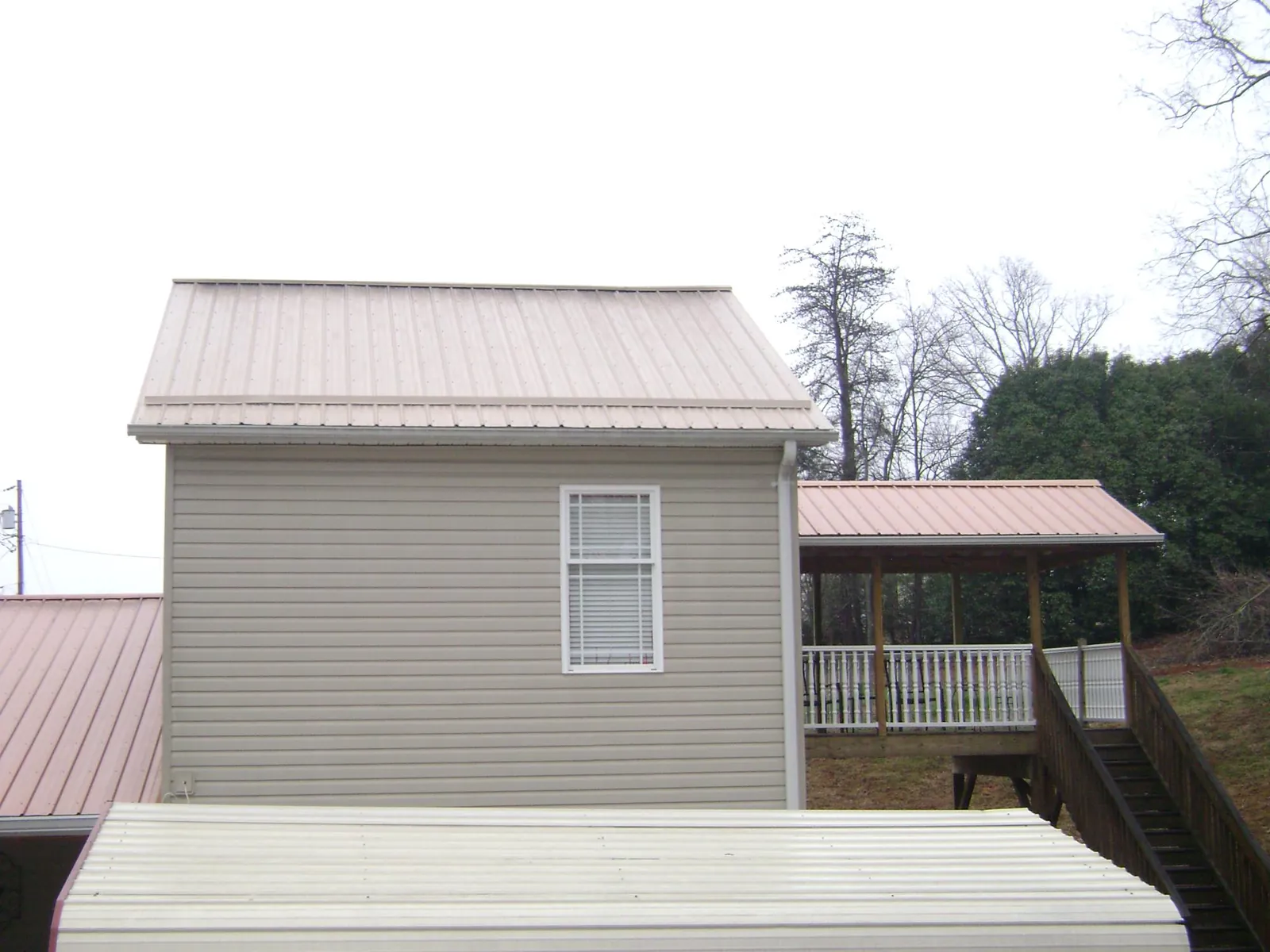Tan metal roofs on a two story addition and attached porch, from a Roof Replacement job in Manns Choice
