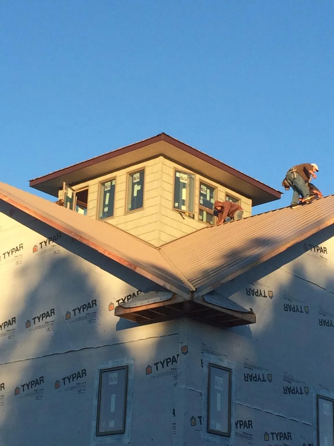 Roofers working around a rooftop cupola on a new metal roof at sunset — Roof Waterproofing in Manns Choice by Roofing Brothers